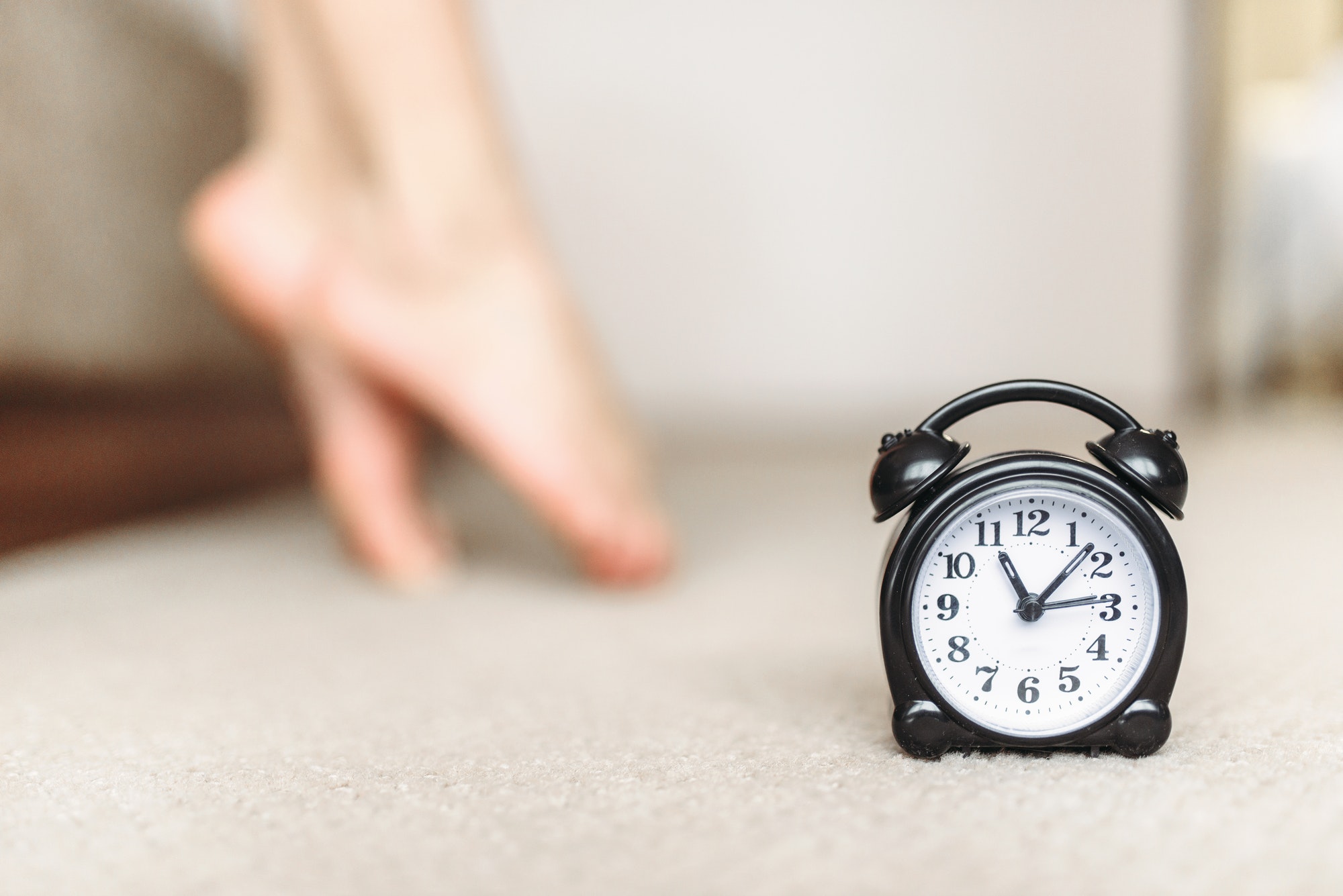 Alarm clock, female legs, waking up concept