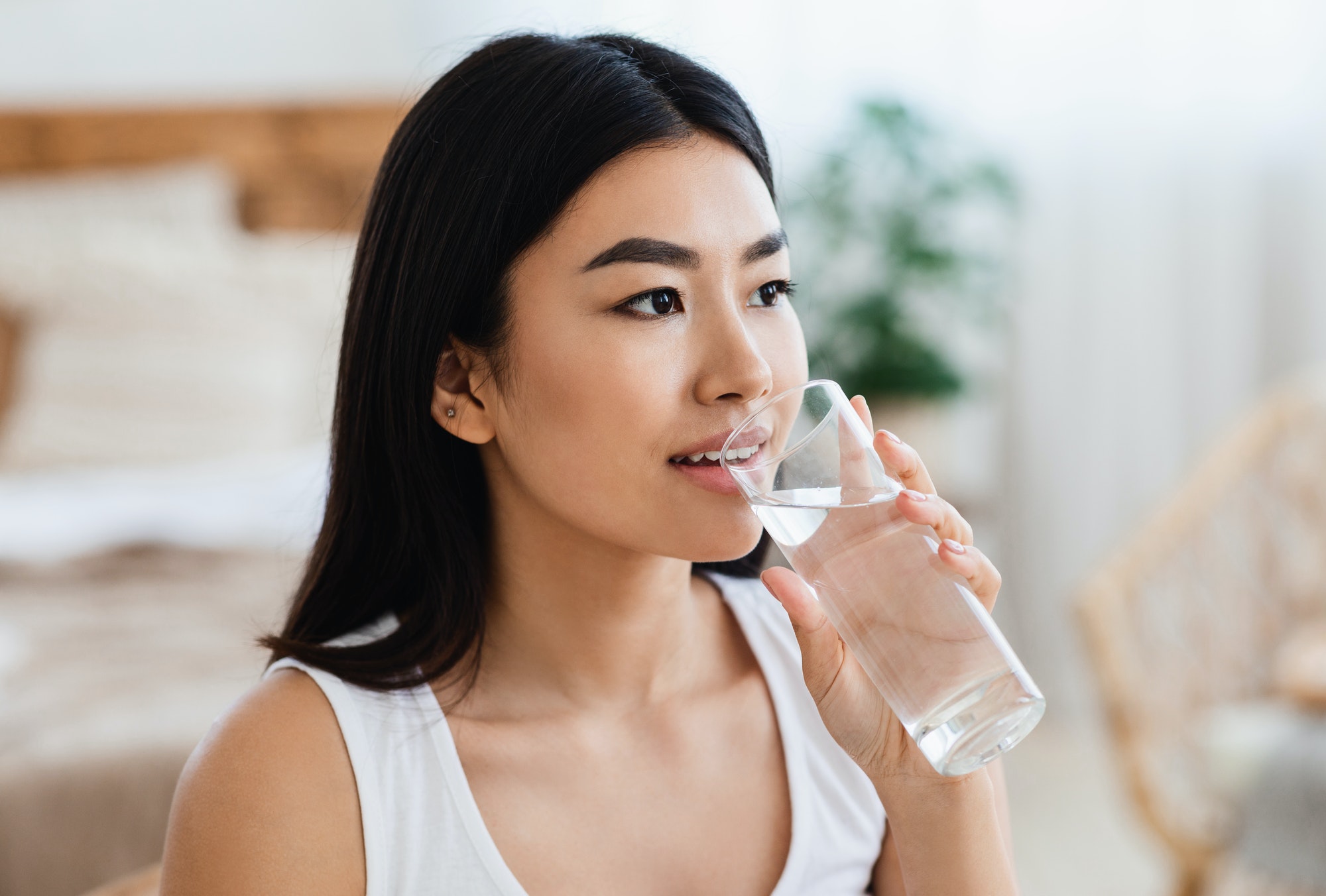 Young asian girl drinking water at bedroom at home