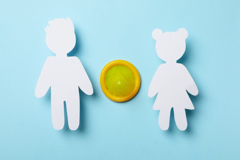 Paper boy and girl and condom on blue background