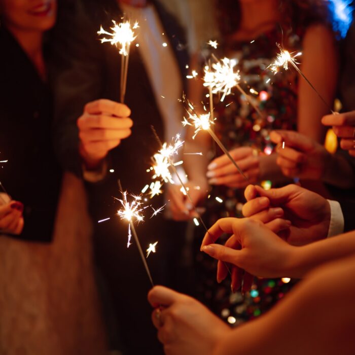 Sparkling sparklers in hands. Playing firework to celebrate winter holidays with friends at party