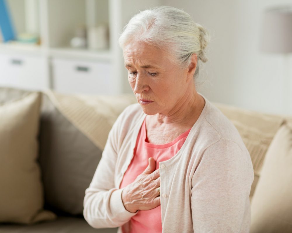 senior woman suffering from heartache at home